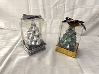 Silver and green scented tree ornaments in boxes side by side