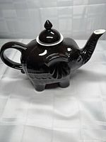Left-front view of glossy black elephant teapot showing lid and spout