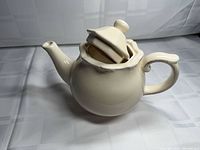 Teapot side view with lid resting inside opening