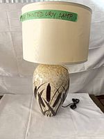 Front view of ceramic table lamp with drum shade and cord visible