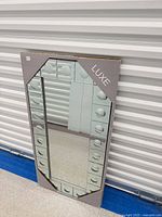 Full view of mirror in packaging leaning against wall