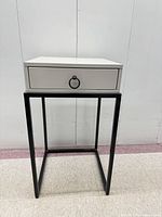 Full view of accent table showing wood top, drawer, black metal base