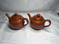 Both ceramic teapots side by side showing bodies, handles, spouts, lids