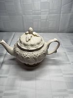 Full left-side view of teapot with lid attached showing embossed pattern
