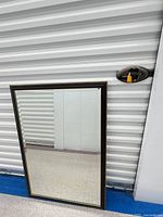 Full view of rectangular mirror leaning against wall