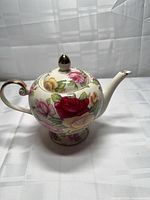 Side view of teapot showing floral pattern, handle and spout