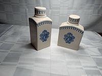 Front view of both ivory/blue ceramic lidded jars