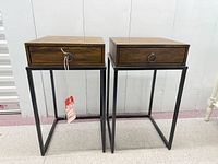 Front view of both matching walnut side tables on black metal bases