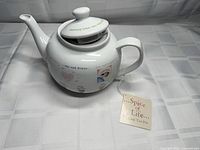Left side view showing teapot body, lid, spout, handle, hang tag