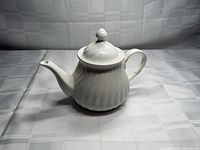 Front view of white ribbed ceramic teapot with lid