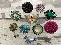 Front view of ten assorted brooches displaying stone colors and designs