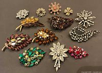 All 13 rhinestone brooches arranged on dark surface