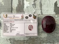 Ruby gemstone next to authenticity certificate showing details