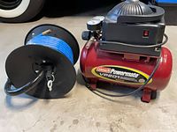 Coleman Powermate VP201 compressor beside hose reel
