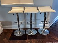 front view of three white bar stools