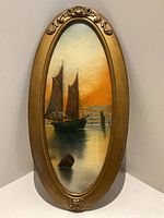 Full view of oval framed sailboat painting