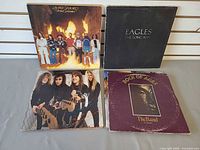 Four LPs: Lynyrd Skynyrd Street Survivors, Eagles The Long Run, Metallica band-photo cover, The Band Rock of Ages