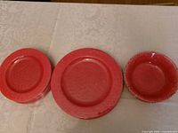 Stacked red dinner plates, salad plates and bowl for scale