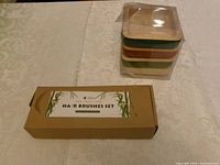 sealed box of bamboo hair brushes beside wrapped stack of wooden trays