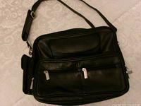 Front view of black leather organizer bag showing compartments and strap