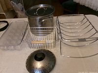 All items laid out on table: stock pot, rack, wire basket, egg tray, steamer insert