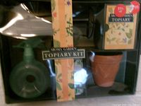 Front view of sealed Aroma Gardens Topiary Kit showing sprayer, pot, shears, tape and instructions