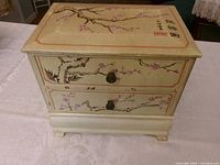 Front view of two-drawer chest showing artwork and knobs