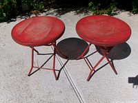 Two red folding patio tables standing upright on patio surface