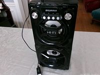 Full view of Sylvania speaker showing dual drivers and charger cable