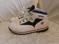 Left side view of both Timberland sneakers showing leather upper, navy inserts, red logo, eyelets and outsole