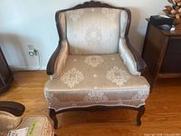 Front view of upholstered armchair showing full seat, crest and cabriole legs