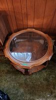 Top view of round wood coffee table showing glass inset and scalloped wood edge