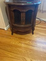 Front view of round drum table showing single lattice door and cabriole legs