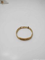 Top view of closed gold bracelet showing exterior pattern and clasp