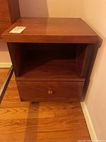 Front view of nightstand showing open shelf, drawer, knob, veneer