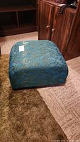 Front angled view of square ottoman showing patterned upholstery