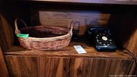 Rotary phone and wicker basket side by side on wooden shelf