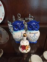 Group shot showing two owl shakers, four egg coddlers behind, and floral bell in foreground