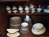 Cabinet view showing stacked dinnerware with brown and gold band trim