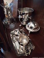 Full group of silver-plate coffee service pieces in cabinet