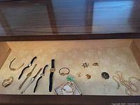 Drawer view showing watches, pearls, cufflinks, brooches and necklace