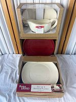 Stacked view of boxed gravy boat & saucer set and two boxed dinner plate sets