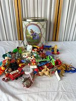 Tin container and full assortment of toys spread on table