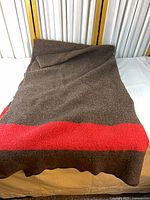 Full view of brown wool blanket laid out showing red stripe across width