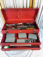 Toolbox open showing top compartment with hand tools and drawers with contents