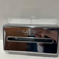 Front view of chrome Kleenex wall tissue dispenser showing embossed logo and slot