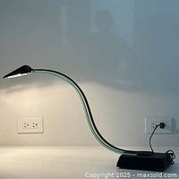Full view of lit lamp showing curved acrylic neck, black base and shade