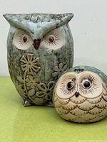 Both ceramic owl figurines together showing size difference and glaze color