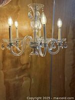 full view of five-arm crystal chandelier lit with test bulbs