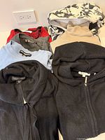 Group of assorted sweaters and hoodies displayed on surface